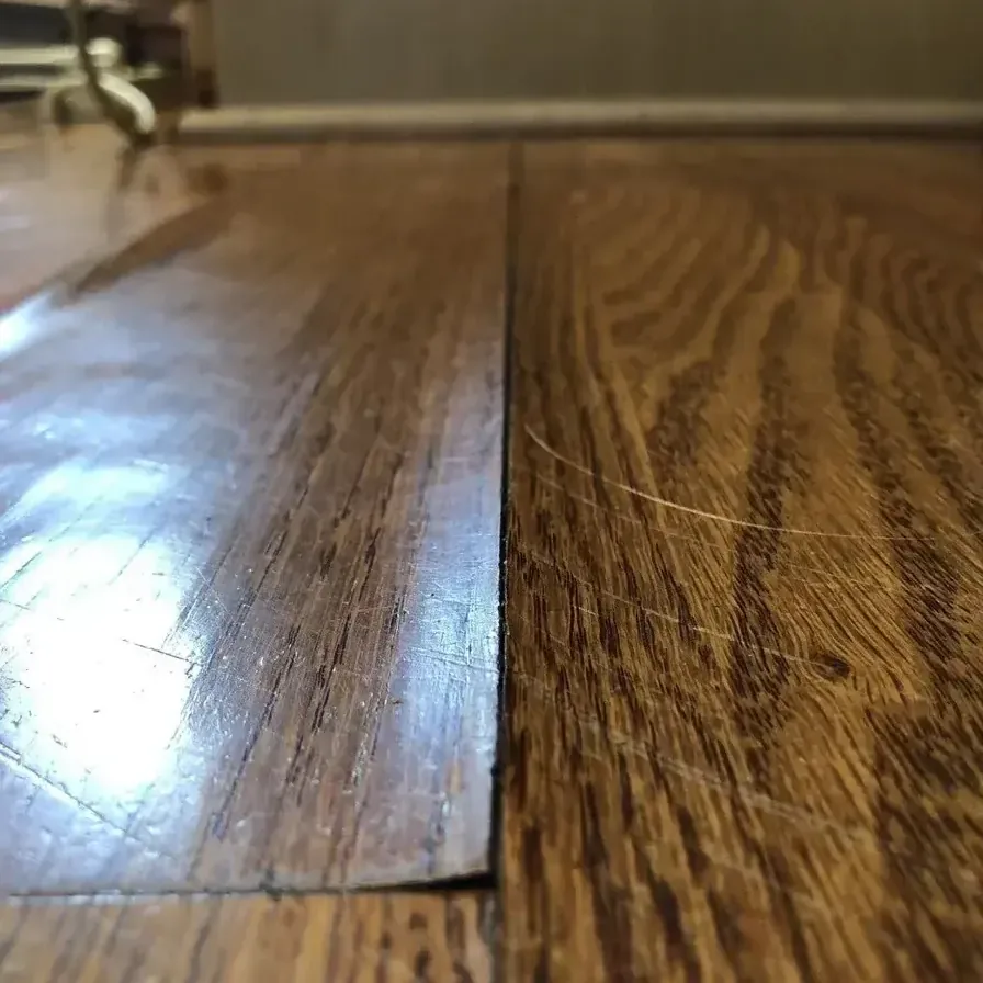 Close view of a hardwood floor where two boards meet, one edge sitting higher than the other