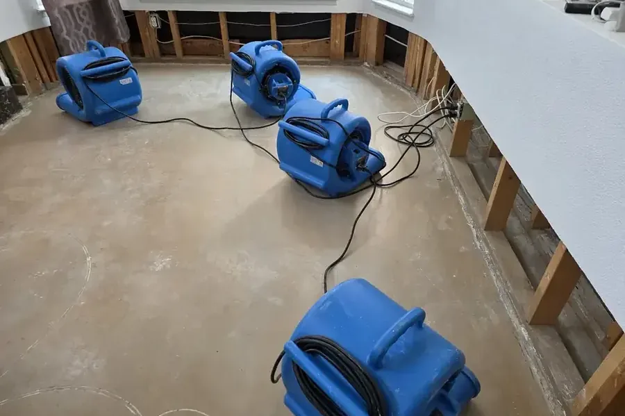 Air movers drying a room after the lower drywall was cut away
